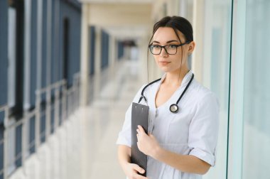 Kadın doktor hastanede dosyayla bekliyor.