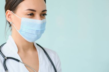 Üniforma ve koruyucu maske takan genç, güzel bir kadın doktor portresi..
