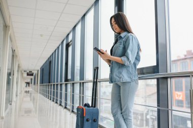 Turizm, tatil, tatil, çocukluk ve Ulaştırma kavramı - seyahat çantası ile küçük kız Havaalanı arka plan üzerinde gülümseyen.
