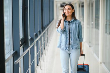 Turizm, tatil, tatil, çocukluk ve Ulaştırma kavramı - seyahat çantası ile küçük kız Havaalanı arka plan üzerinde gülümseyen.