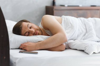 evde onun yatakta yatarken gülen yakışıklı adam.