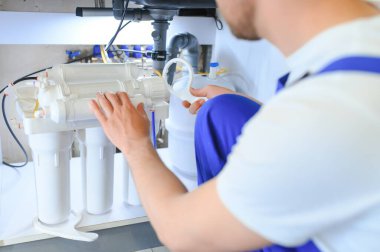 Tesisatçı su filtresi kurar ya da değiştirir. Yerleştirme su filtresi. Tamirci mutfağa su filtresi koyuyor. Ters osmoz su arıtma sisteminin kurulumu