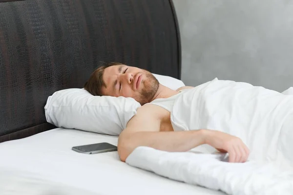 stock image Handsome man sleeping under soft blanket in bed at home.