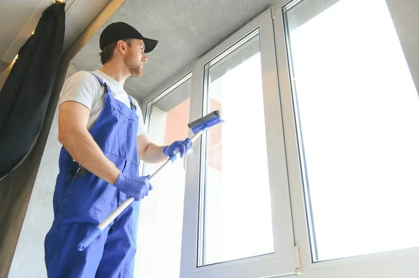 Cheerful male person cleaning window.