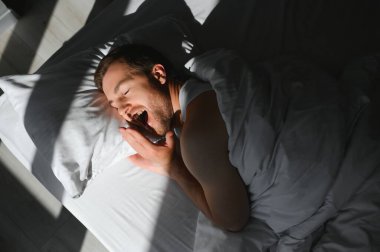Mutlu genç sakallı adam evdeki yatakta dinleniyor..