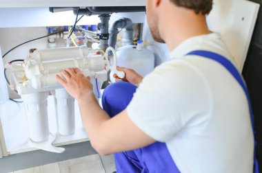 Tesisatçı mutfaktaki su için kartuş filtresi değiştiriyor. Kavram filtreleme sistemi