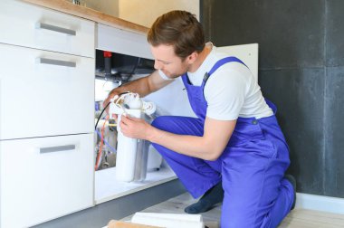 Tesisatçı su filtresi kurar ya da değiştirir. Yerleştirme su filtresi. Tamirci mutfağa su filtresi koyuyor. Ters osmoz su arıtma sisteminin kurulumu