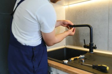 Profesyonel tesisatçı mutfakta musluk tamir ediyor..