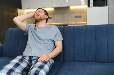 Genç adam evde akşamdan kalma acı sabahında.