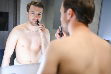 yakışıklı genç düzeltici ile onun burun saç kaldırmak.