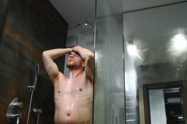 Yakışıklı genç adam duşa giriyor. Düşen suyun altında duruyor. Çıplak bedenini yıkıyor ve evdeki modern banyoda kafasını yıkıyor. Erkek Modeli.