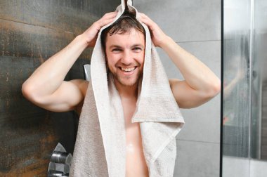 Genç bir adam duştan sonra kendini havluyla siler.
