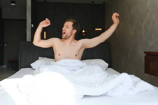 stock image Happy young bearded man is relaxing on the bed at home.