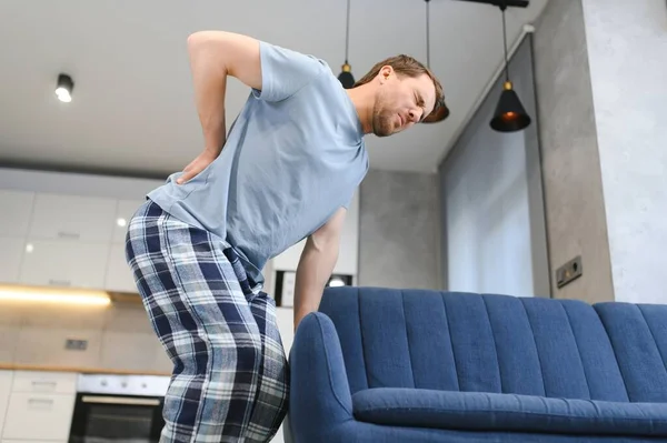 Handsome man lifting sofa and feeling pain. man droped sofa because of painful back.