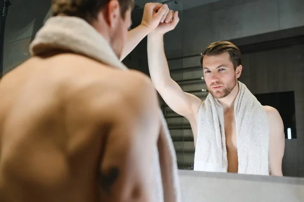 stock image Handsome shirtless man looking in the mirror in the bathroom.