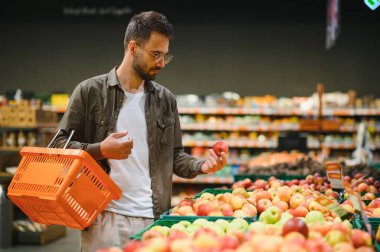 Yakışıklı adam bir süpermarkette alışveriş.