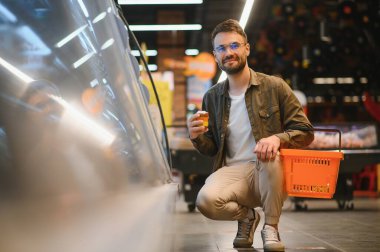 Yakışıklı genç adam markette dondurulmuş yiyecek var mı diye buzdolabına bak.