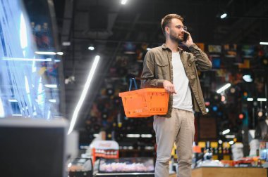 Yakışıklı adam bakkal gıda ürünleri Başlangıç rafı seçme süpermarkette alışveriş gülümseyen portresi.