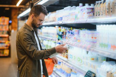 Yakışıklı adam bakkal gıda ürünleri Başlangıç rafı seçme süpermarkette alışveriş gülümseyen portresi.