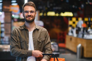 Yakışıklı adam bakkal gıda ürünleri Başlangıç rafı seçme süpermarkette alışveriş gülümseyen portresi.