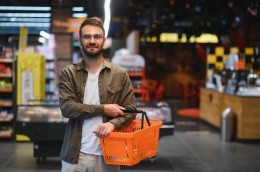 Yakışıklı adam, modern süpermarketten ya da marketten sağlıklı yiyecek ve içecek alıyor. Yaşam tarzı ve tüketim konsepti.
