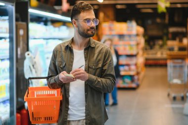 Yakışıklı adam bir süpermarkette alışveriş.
