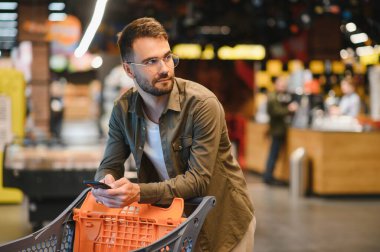 Yakışıklı adam bir süpermarkette alışveriş.