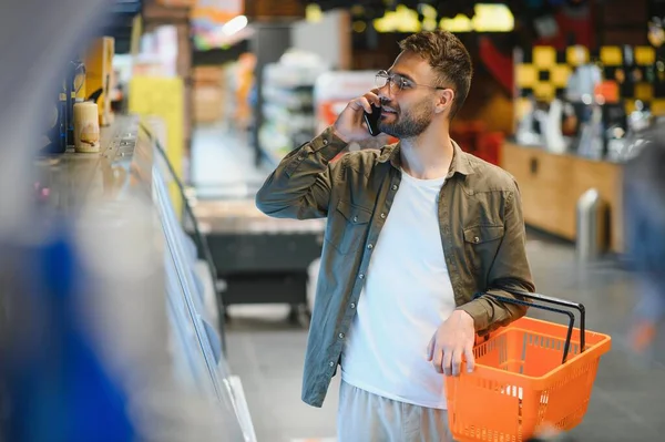 Yakışıklı genç adam süpermarkette yemek seçiyor.