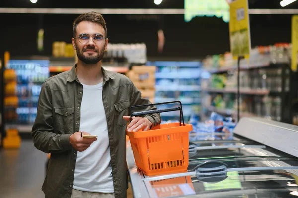 A handsome young man in a grocery store chooses food products
