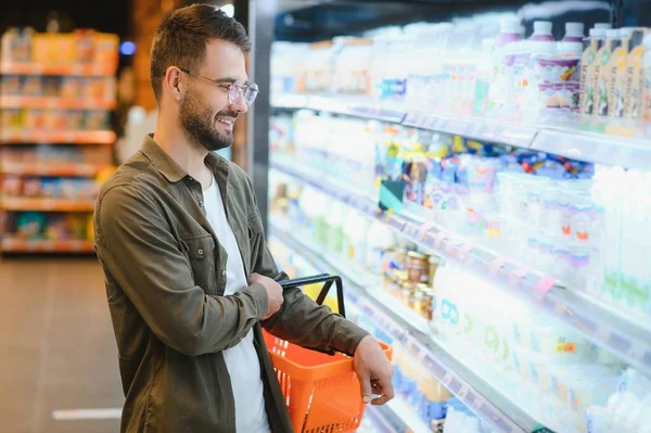 A handsome young man in a grocery store chooses food products