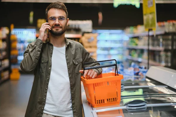 Bello Shopping Uomo Nel Supermercato Sorridente Utilizzando Telefono — Foto Stock