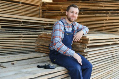 Bir kereste fabrikasının sanayi deposunda çalışan biri açık havada kereste fabrikasındaki bitmiş ürünlere el atıyor.