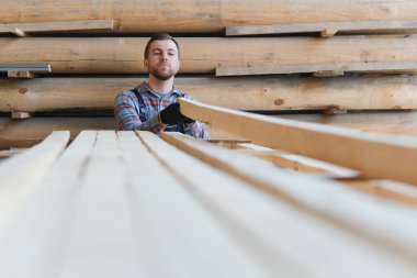 Üniformalı marangoz kereste fabrikasının tahtalarını kontrol ediyor..