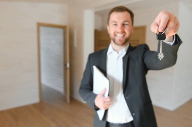 Bir takım elbise Smiles ve teklifler anahtarları yeni bir daire başarılı Emlak ajanı. Yenilenmiş olmak Oda ortasında ayakta. Profesyonel gayrimenkul broker tarafından Satılık geniş yeni ev