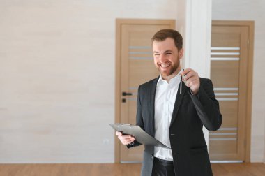 Bir takım elbise Smiles ve teklifler anahtarları yeni bir daire başarılı Emlak ajanı. Yenilenmiş olmak Oda ortasında ayakta. Profesyonel gayrimenkul broker tarafından Satılık geniş yeni ev