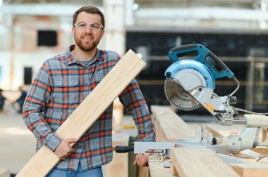 Ahşap bıçkıhanede elektrikli testere ile tahta kesme konusunda usta bir dolap ustası. Profesyonel dolap yapımcısı kereste fabrikasında testere kullanıyor. Ahşap mobilya üretimi