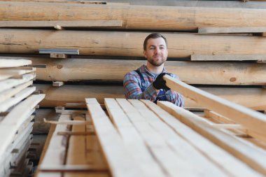 Üniformalı marangoz kereste fabrikasının tahtalarını kontrol ediyor..
