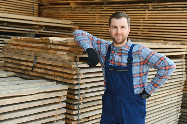 stock image Carpenter in uniform check boards on sawmill.