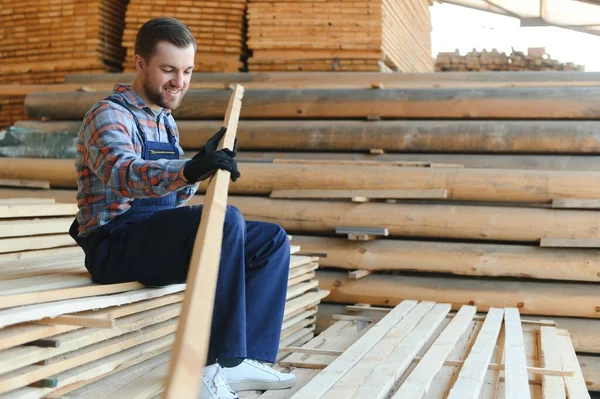 stock image Industrial warehouse of a sawmill, an employee puts his hands on the finished products at the sawmill in the open air