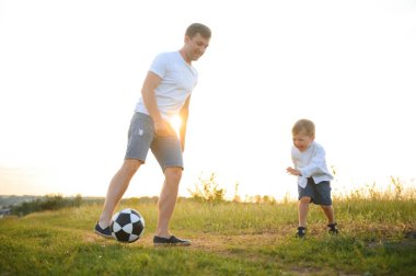 Genç baba ve küçük oğlu futbol oynuyorlar, babalar günü.