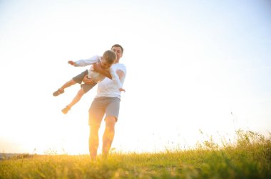 Babalar Günü. Baba ve oğul yazın dışarıda birlikte oynuyorlar. Mutlu aile, baba, oğul gün batımında