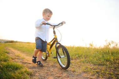 Yaz tarlasında bisikleti olan yakışıklı bir çocuk.