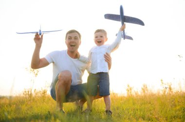 Baba ve oğlu gün batımında doğada. Bir baba oğluyla gün batımında oyuncak uçaklarla oynar. Babalar Günü.