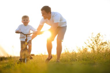 Baba oğluna bisiklet sürmeyi öğretiyor..