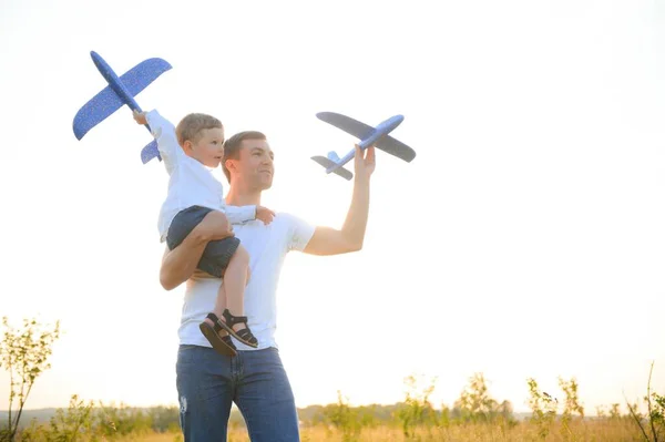 Stock image Cute little boy and his handsome young dad are smiling while playing with a toy airplane in the park