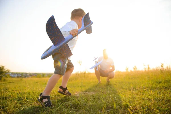 自然の中で日没で彼の息子とお父さん 父は日没時に息子とおもちゃの飛行機で遊ぶ 父の日 — ストック写真