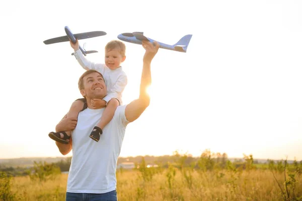 Stock image Cute little boy and his handsome young dad are smiling while playing with a toy airplane in the park