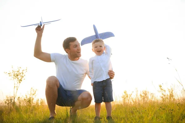 stock image Happy father child moment. Father piggybacking his boy at sunset while he's playing with toy plane