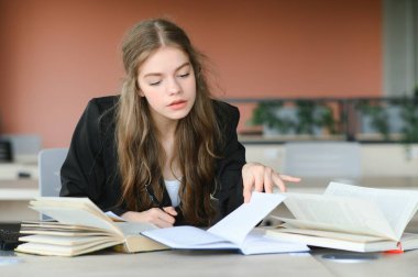 Eğitim ve okul konsepti - Öğrenci kız okulda okuyor ve kitap okuyor