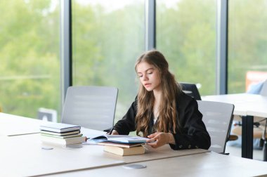 Eğitim ve okul konsepti - Öğrenci kız okulda okuyor ve kitap okuyor